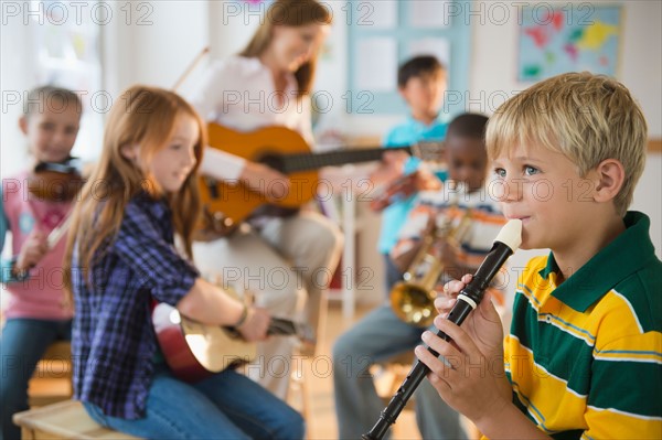 School children (8-9) with teacher playing instruments during music class