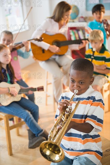 School children (8-9) with teacher playing instruments during music class