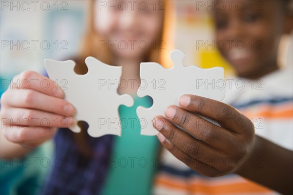 Close up of children's (8-9) hands holding jigsaw pieces