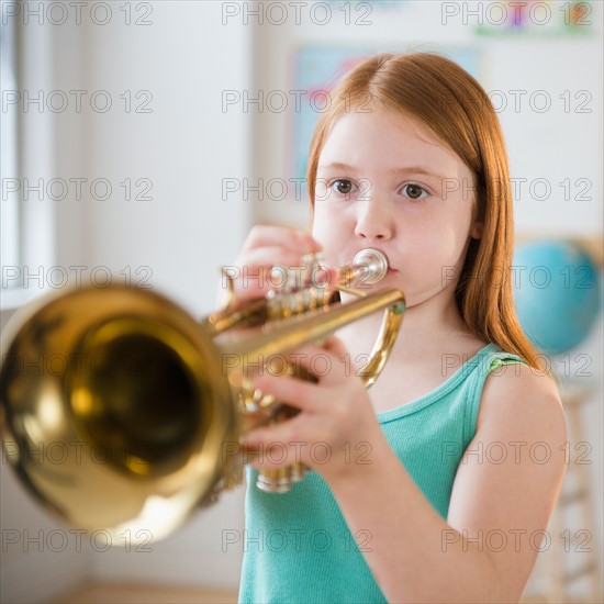 Portrait of school girl (8-9) playing trumpet during music class