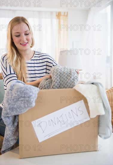 Young woman packing clothes for donation