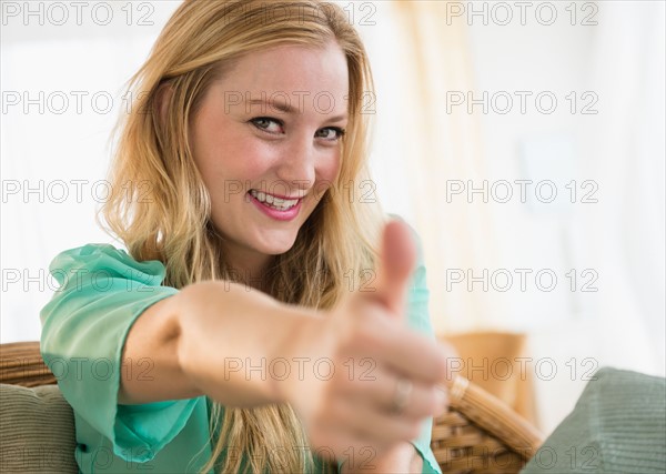 Portrait of young woman with thumbs up