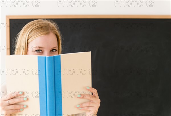 Portrait of woman shielding her face with book