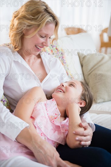 Mother and daughter (8-9 years) relaxing on sofa