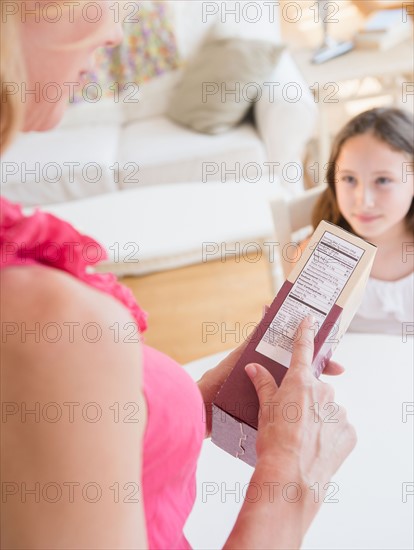 Mother reading nutrition label, daughter (8-9 years) in background