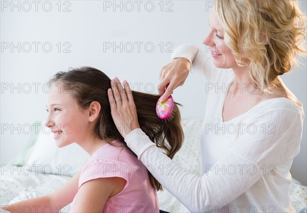 Mother combing daughter's (8-9 years) hair