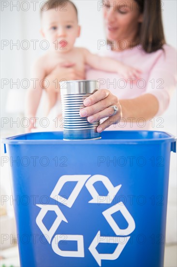 Mother and daughter (6-11 months) putting can into recycling bin