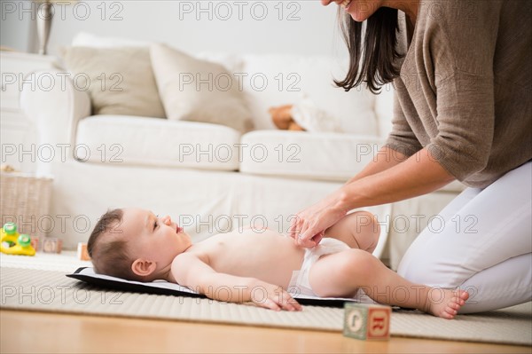 Mother changing diaper to daughter (6-11 months)