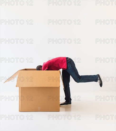 Studio shot of young man with large cardboard box