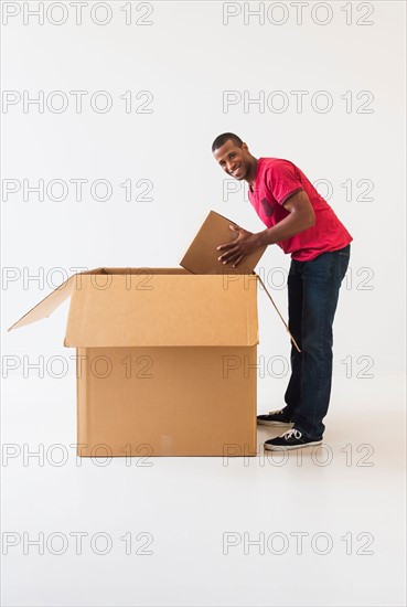 Studio shot of young man with large cardboard box