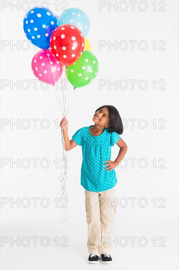 Studio shot of girl (6-7 years) holding colorful balloons