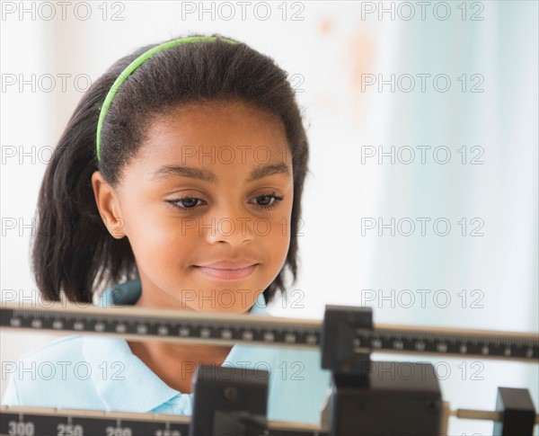 Girl (6-7 years) standing on weight scale