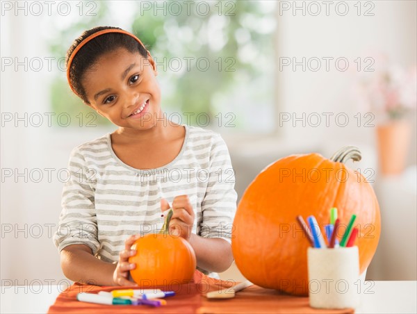 Portrait of smiling girl (6-7) making Jack-o-lantern