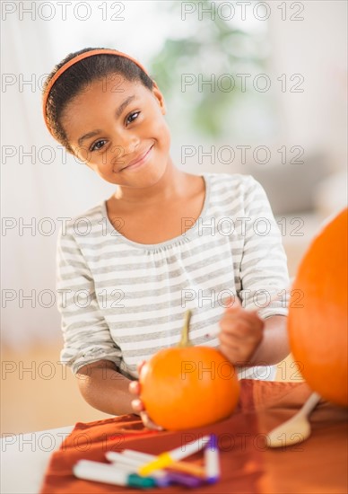 Portrait of smiling girl (6-7) making Jack-o-lantern