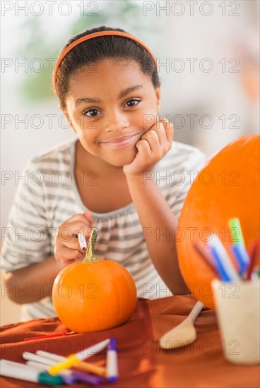 Portrait of smiling girl (6-7) making Jack-o-lantern