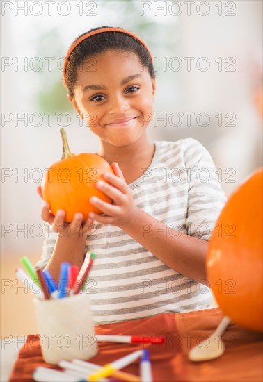 Portrait of smiling girl (6-7) making Jack-o-lantern