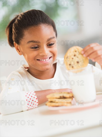 Girl (6-7) having cookie and milk