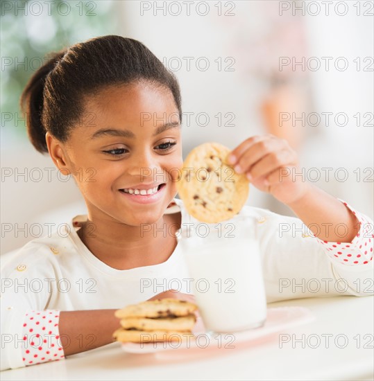 Girl (6-7) having cookie and milk