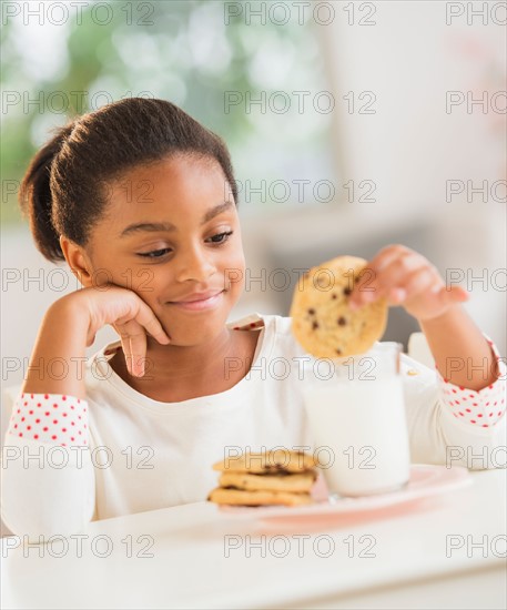 Girl (6-7) having cookie and milk