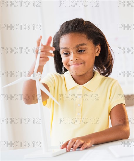 Smiling girl (6-7) playing with wind turbine model