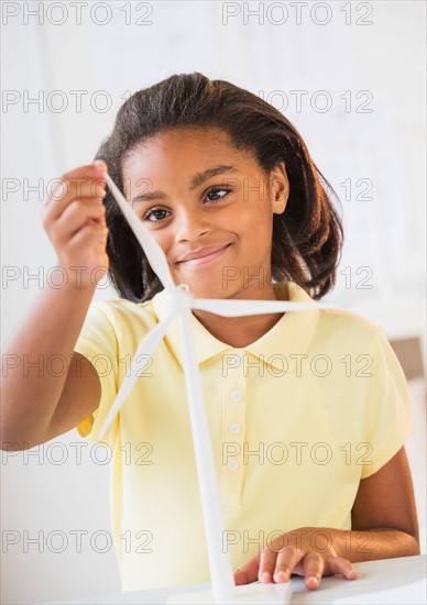 Smiling girl (6-7) playing with wind turbine model