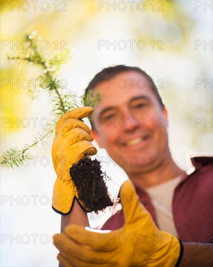 Portrait of man holding tree seedling