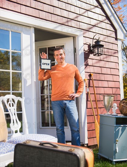 Portrait of man holding up open sign