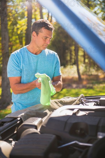 Man standing by car with hood open at roadside