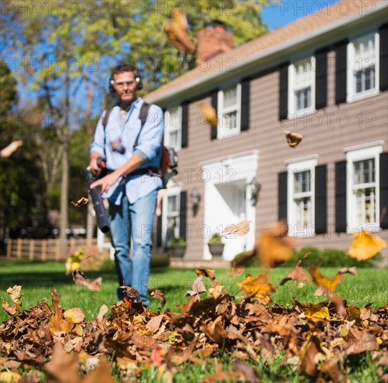 Man using leaf blower in front yard