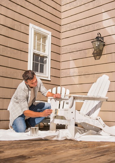 Portrait of man painting deck chair