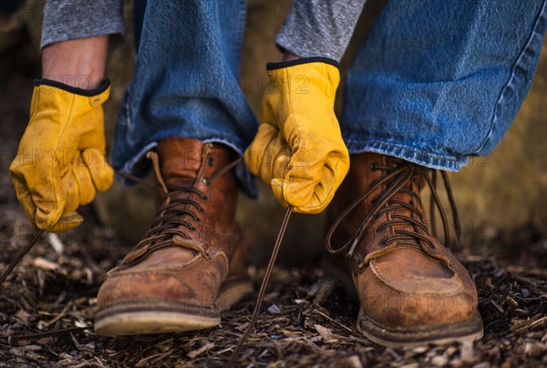 Male tying shoes in protective gloves