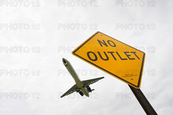 Low angle view of airplane over road sign