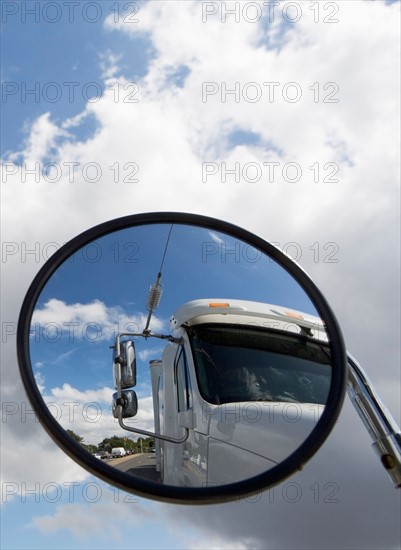 Reflection of semi-truck in side view mirror