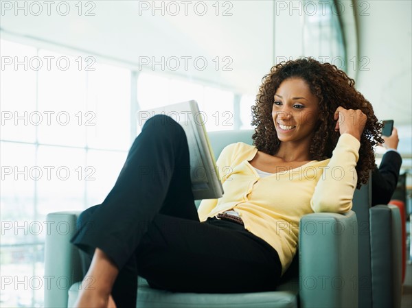 Smiling woman using digital tablet while waiting in lobby