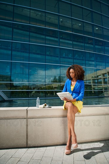 Young woman using digital tablet on ledge
