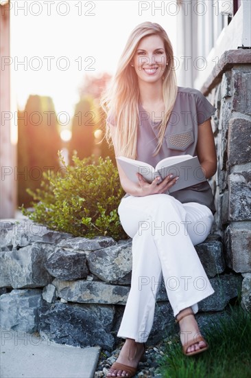 Portrait of woman sitting outdoors and holding book