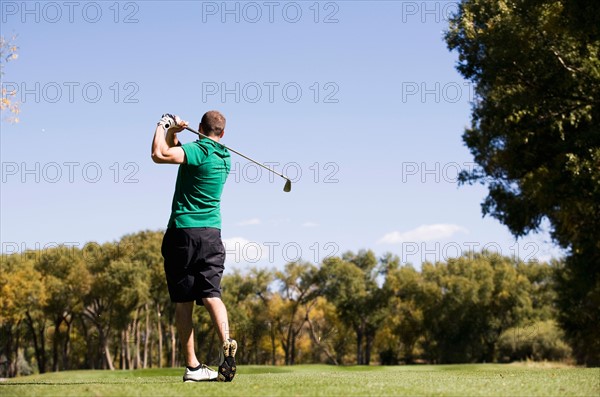 Rear view of man hitting ball on golf course