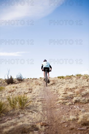 Rear view of man biking on trial