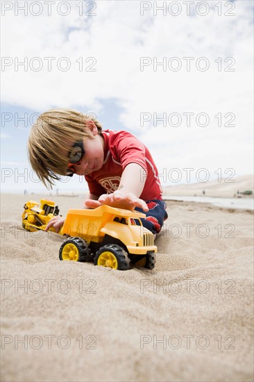 Boy (4-5) playing with truck in sand