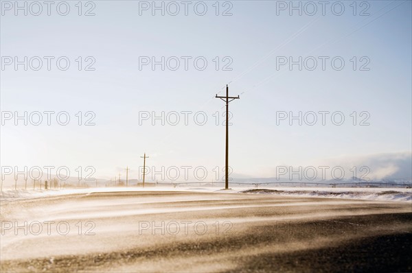 Snow blowing across rural road