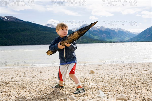 Boy (2-3) holding piece of wood