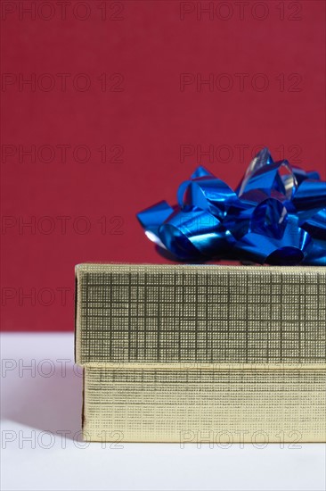 Studio shot of gift with blue bow on red background
