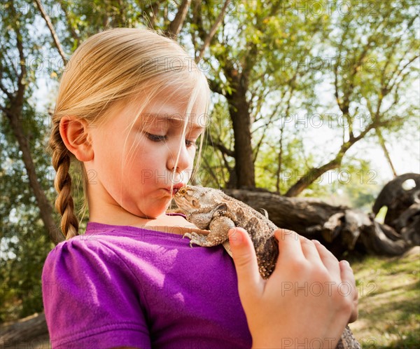 Little girl (4-5) kissing lizard