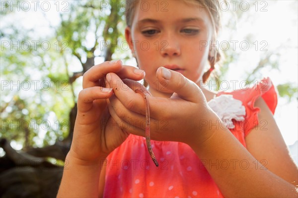 Little girl (6-7) holding earthworm