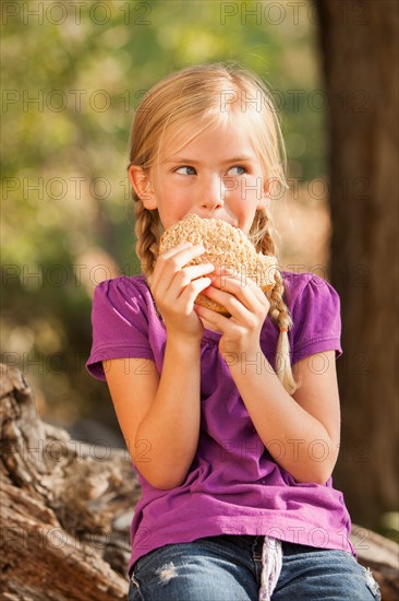 Little girl (4-5) eating peanut butter and jelly sandwich