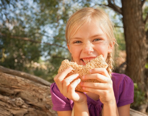 Little girl (4-5) eating peanut butter and jelly sandwich