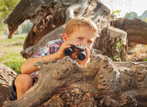 Little boy (6-7) looking at something in the distance with binoculars