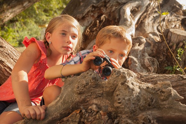 Little boy and little girl (6-7) looking at something in the distance with binoculars