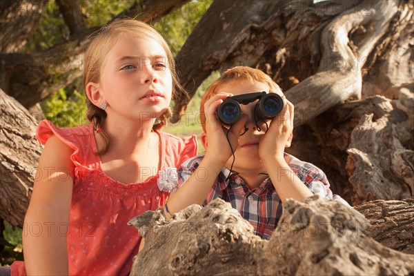 Little boy and little girl (6-7) looking at something in the distance with binoculars