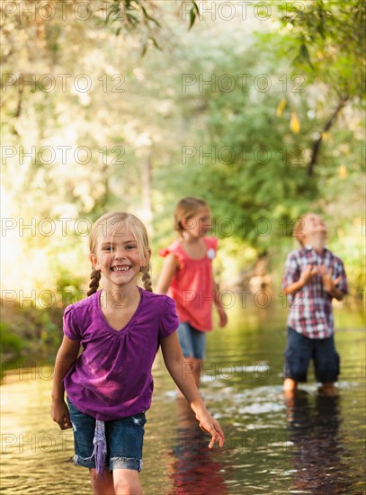 Little girl (4-5) in foreground standing in small stream with friends (6-7)